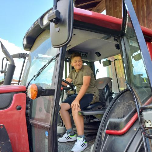 Junge sitzt stolz auf dem Fahrersitz eines Traktors