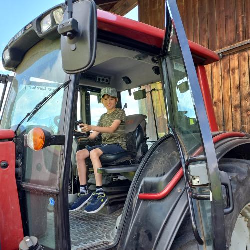 Junge sitzt stolz auf dem Fahrersitz eines Traktors